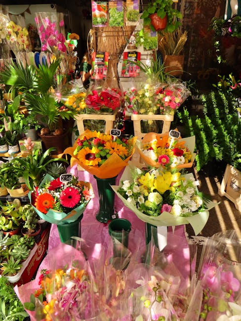 A vibrant display of freshly arranged floral bouquets and potted plants at Chiswick Flowers, showcasing a variety of bright-colored flowers including pink, yellow, white, and orange blooms. The bouque